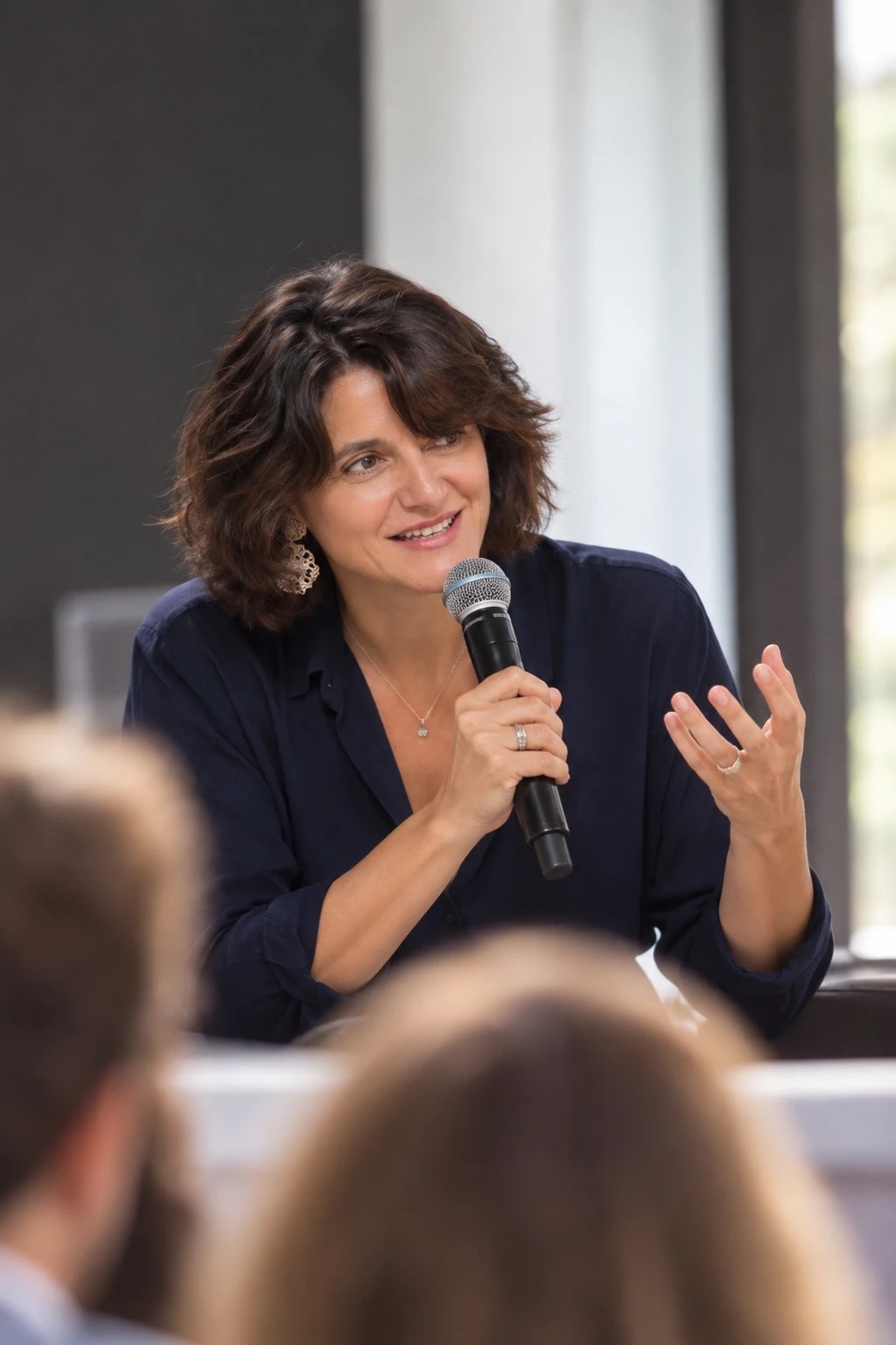 Bernardette M. speaking with a microphone at a panel.